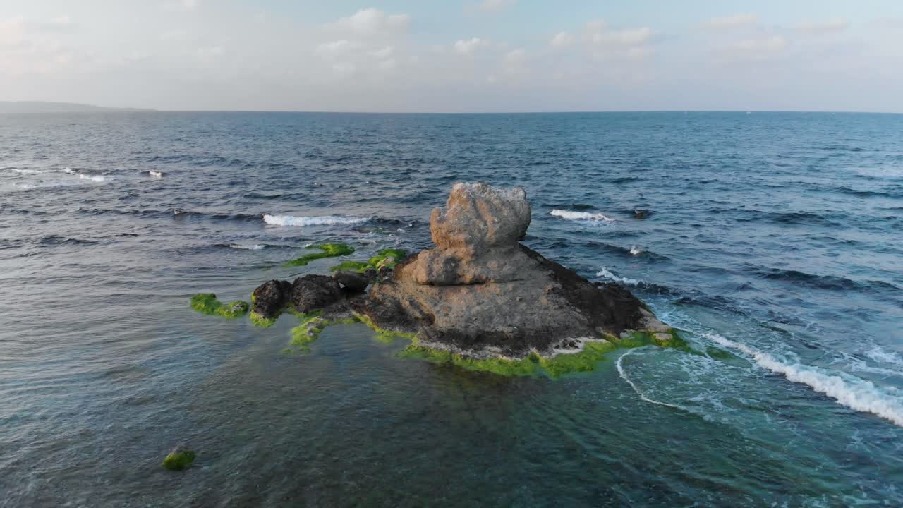 аэрофотосъемка с параллаксом вокруг скалы в море на закате