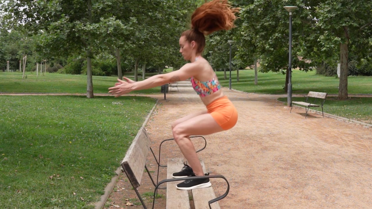 Una giovane donna fa esercizi su una panchina in un parco, mostrando uno stile di vita attivo e sano.