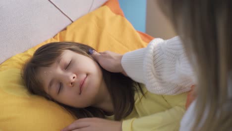 mom prepares her cute little daughter for sleep, strokes her hair, loves it.