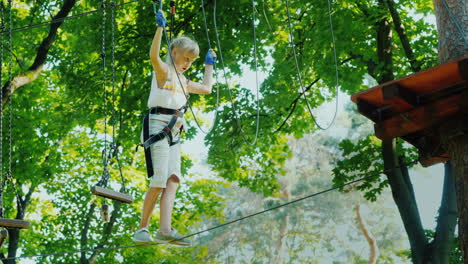 a brave child walks along a tightrope between tall trees active childhood and fun