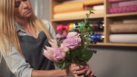 Junge-Blonde-Floristin-Arrangiert-Einen-Modernen-Blumenstrauß-Und-Schaut,-Wie-Die-Blumen-Kombiniert-Werden.-Hübscher-Besitzer-Einer-Blumenaufnahme