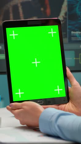 vertical video: close up of scientist woman holding tablet with green mockup