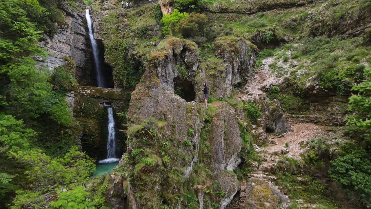 man preparing to enter a cave and discover the Uj&euml;vara and Peshtur&euml;s waterfalls at the top of a mountain in Albania
