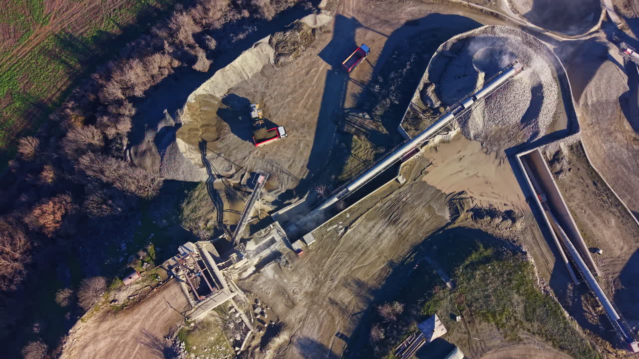 Construction site bustling with activity showcasing machinery, materials, and land preparation near a green landscape under clear blue skies