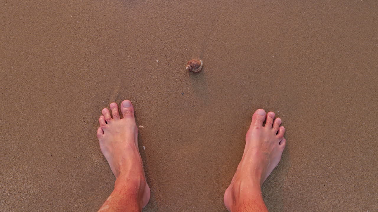 Fale oceanu obmywające stopy na piaszczystej plaży.