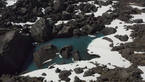 flying over turquoise glacial pools surrounded by incredible snow covered grey rocks, nature drone aerial iceland