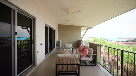 large apartment balcony with staged outdoor furnishing seat cushions and ceiling fan above table on sunny day