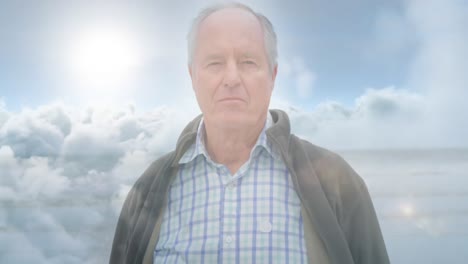 Animation-of-glowing-light-over-serious-senior-man-over-clouds