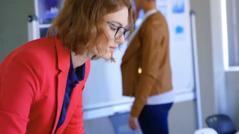 Side-view-of-young-caucasian-businesswoman-looking-at-laptop-in-modern-office-4k