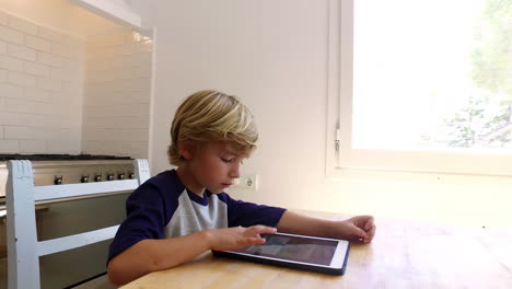 handheld arc shot of boy using tablet computer in kitchen