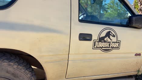 jurassic park sticker on the side of a beige parked off-road car