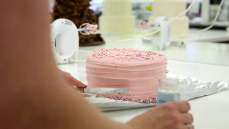 mujer en la panadería decorando pastel con salpicaduras de azúcar