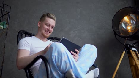 man using tablet in a rocking chair