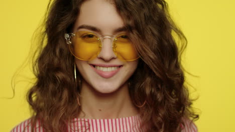 young woman in sunglasses on yellow background