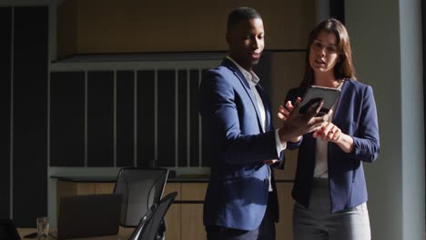 diverse businessman and businesswoman discussing and using tablet in modern office