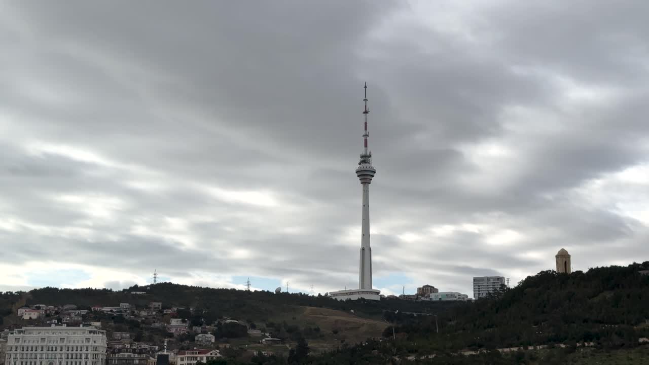 Tall Baku TV Tower rising above hills under dense clouds in Baku, Azerbaijan
