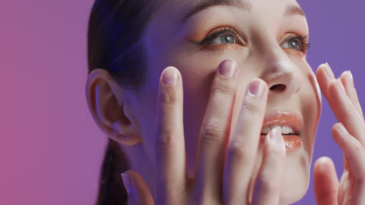 Smiling caucasian woman with brown hair and make up touching her face, copy space, slow motion