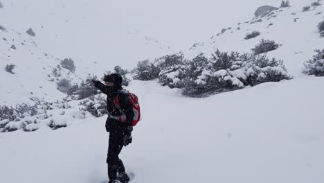 vista trasera de un hombre caminando en las montañas en invierno, cubierto de nieve, usando una mochila