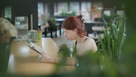 young woman reading and drinking in a cafe