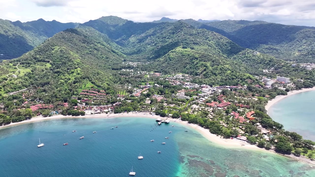 Spiaggia di Senggigi e terminal dei traghetti con hotel fronte mare in estate, sull'isola di Lombok, Indonesia. Ripresa aerea.