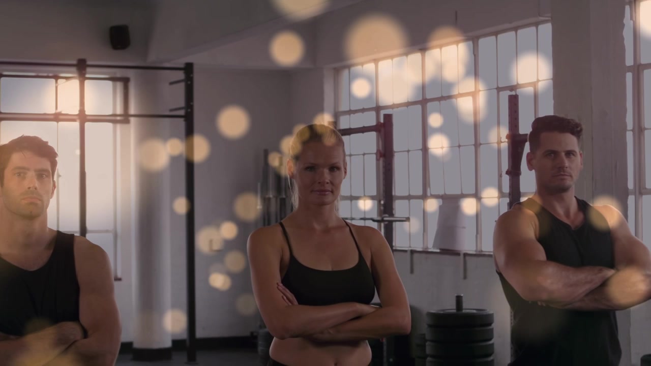Animation of glowing spots over strong man exercising in gym