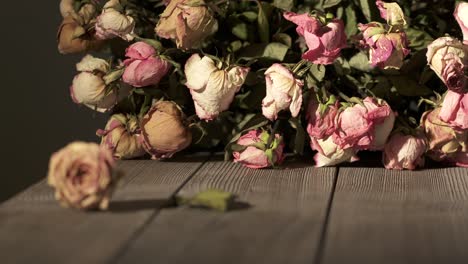 bouquet of withered rose flowers on wooden table. dried pink cream yellow roses