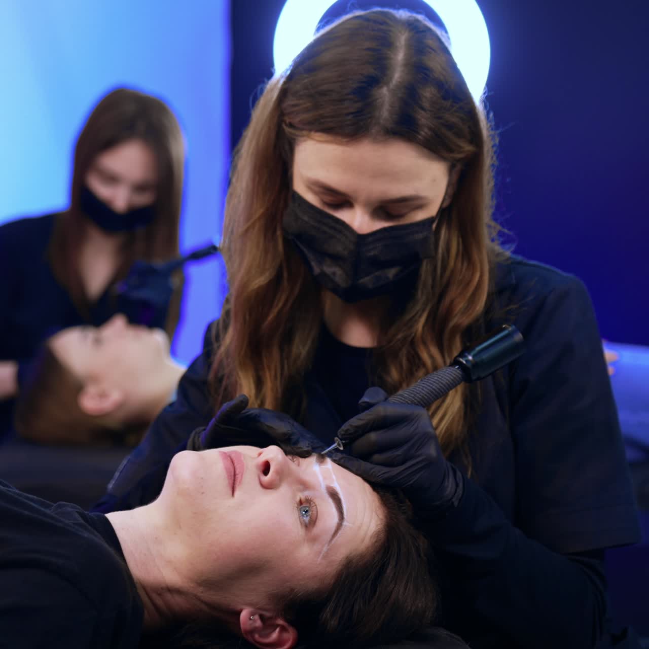 Brunette woman lies on the couch having her eyebrows tattooed. Salon procedure of permanent make up