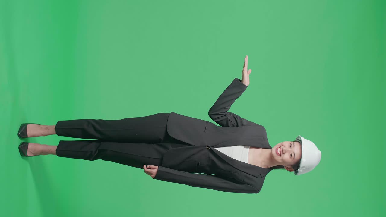 Full Body Of Smiling Asian Female Engineer With Safety Helmet Open Palm Up In Getting Or Receiving Something Gesture, Holding, Showing, Presenting Product In The Green Screen Studio