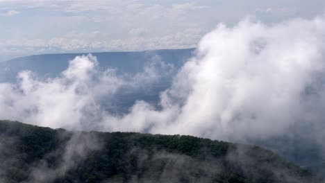 las imágenes portátiles capturan una vista hipnotizante de las montañas mientras las nubes se desvían lentamente de la parte inferior izquierda a la parte superior derecha, envolviendo colinas boscosas exuberantes.