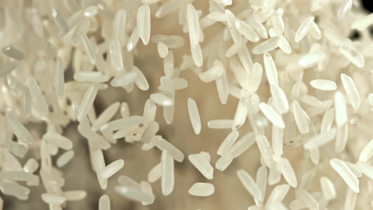Chicchi di riso bianco che fluttuano al rallentatore su sfondo nero
