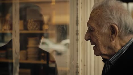 an engaging conversation: a senior man interacts with a reflection in a window while observing the world outside