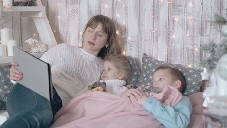 family watches attentively movie on bed with pillows