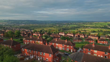 UK-housing-scene:-Aerial-view-of-Yorkshire's-red-brick-council-estate,-bathed-in-morning-sunlight,-with-residents-in-motion