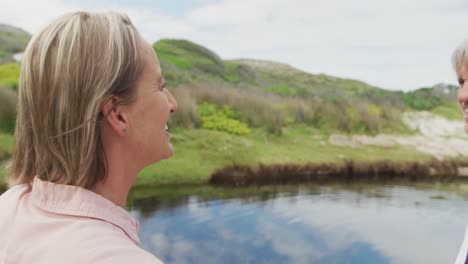 smiling senior caucasian couple embracing at clean river outdoors