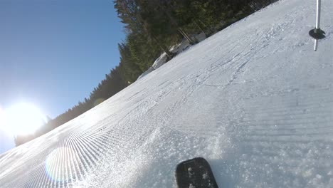 Zeitlupe,-Ein-Skifahrer,-Der-Einen-Steilen-Hang-Hinunterfährt,-Im-Hintergrund-Ein-Blauer-Himmel-Mit-Strahlender-Sonne-Und-Schnee,-Der-Von-Den-Skiern-Aufsteigt.-Blick-Vom-Rücken-Des-Skifahrers