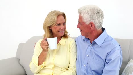 Smiling-retired-couple-chatting-on-the-couch