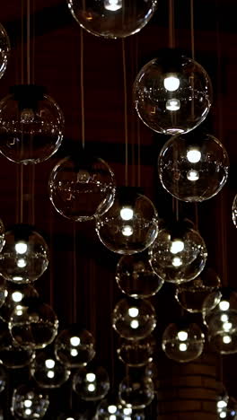 many light bulbs lighting up. dark background with lamps becomes bright. beautiful ceiling with round glass lamps switches on. vertical video