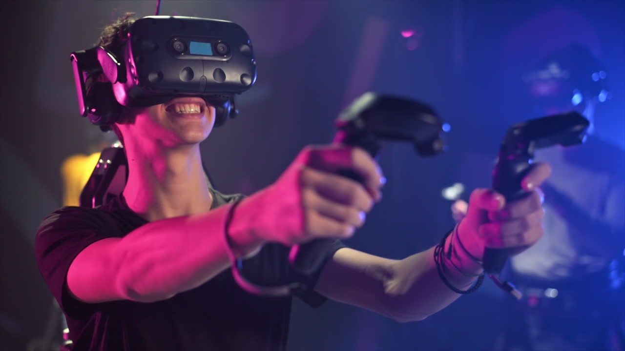 A joyful, interested boy is playing on VR treadmill with helmet, controllers and backpack. Other people playing nearby. Slow motion