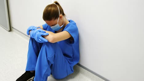 Tensed-female-doctor-sitting-in-corridor