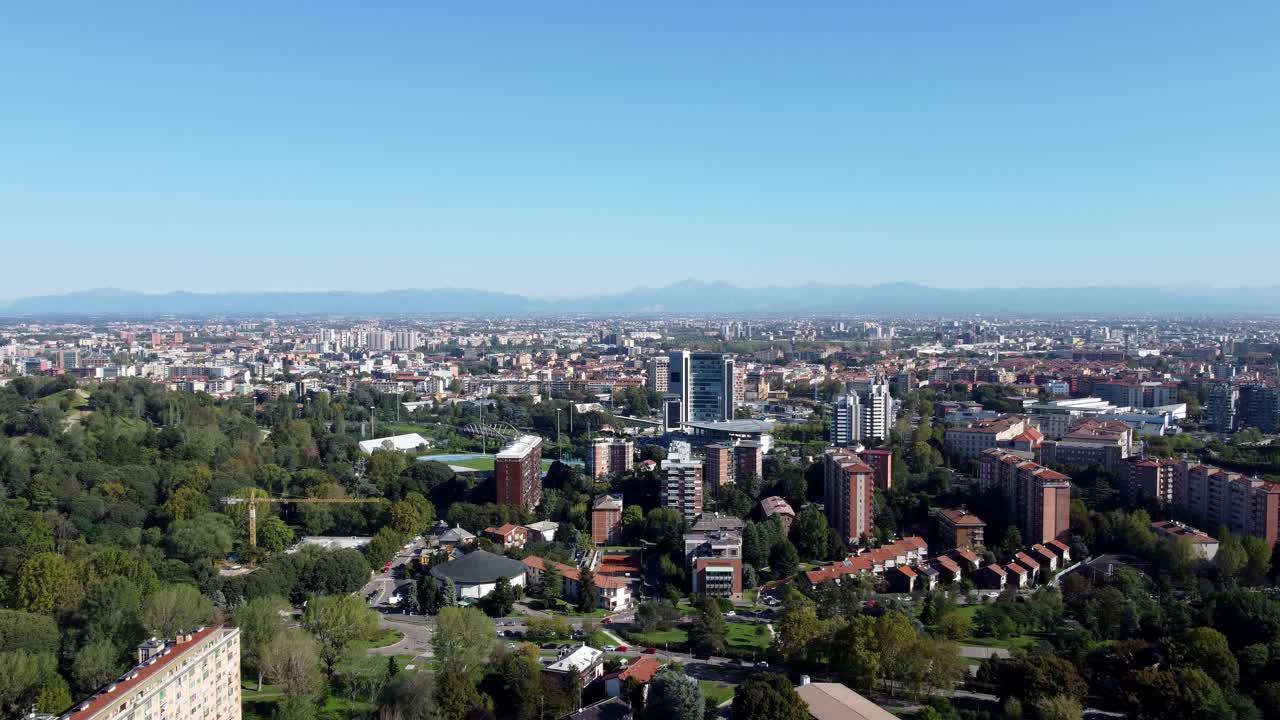 Aerial view of Milan’s skyline, skyscrapers and historic architecture in a wide urban panorama, with italian alps mountains in background during a sunny day clear sky