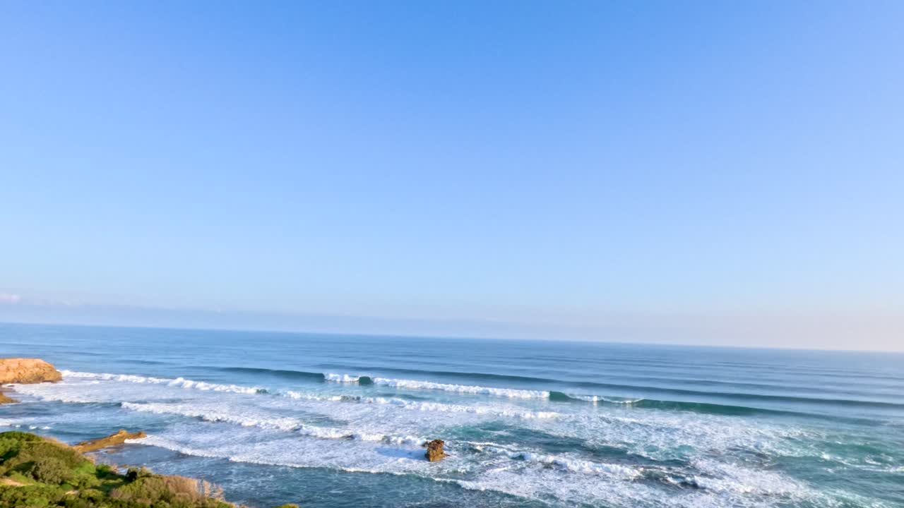 A tranquil view of ocean waves and rocky coastline under clear blue skies, captured at Mornington Peninsula, Australia