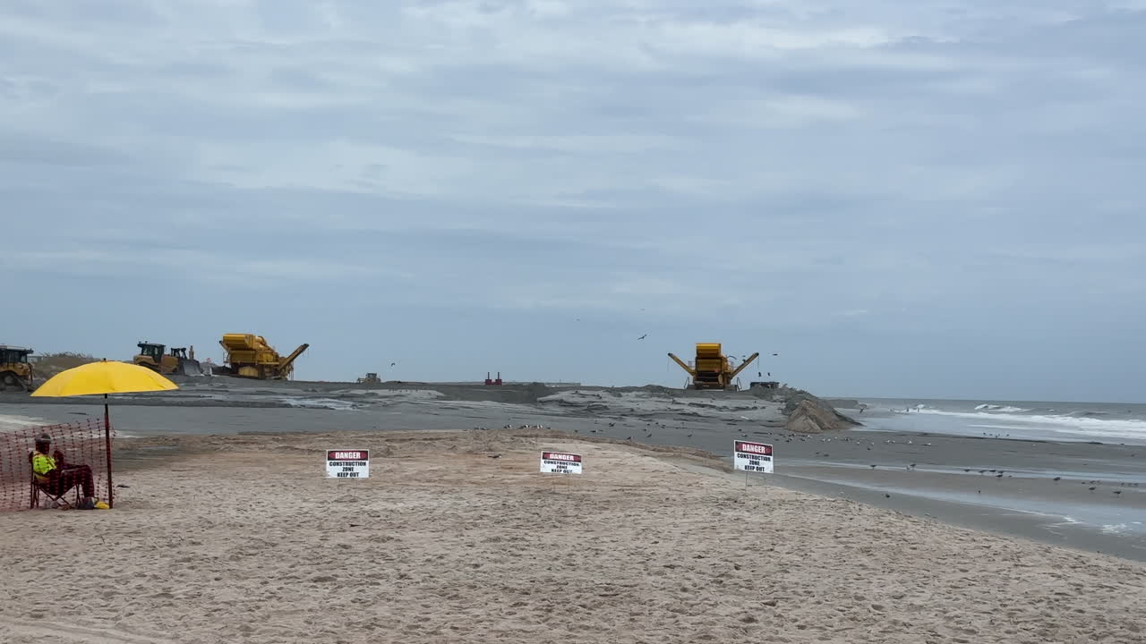 Security guard and warning signs at beach sand replenishment project