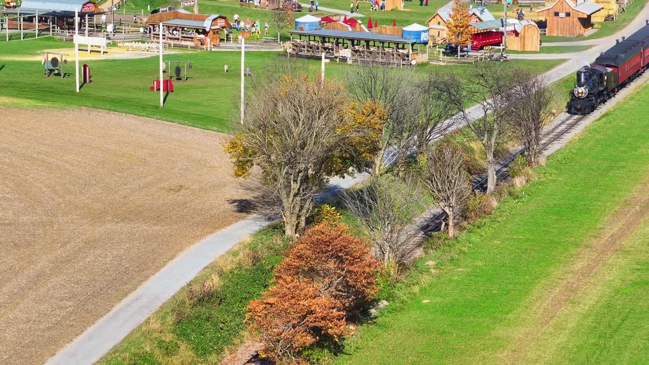 una antena ampliada a la vista de un tren de pasajeros de vapor que se aproxima en una sola vía en el campo