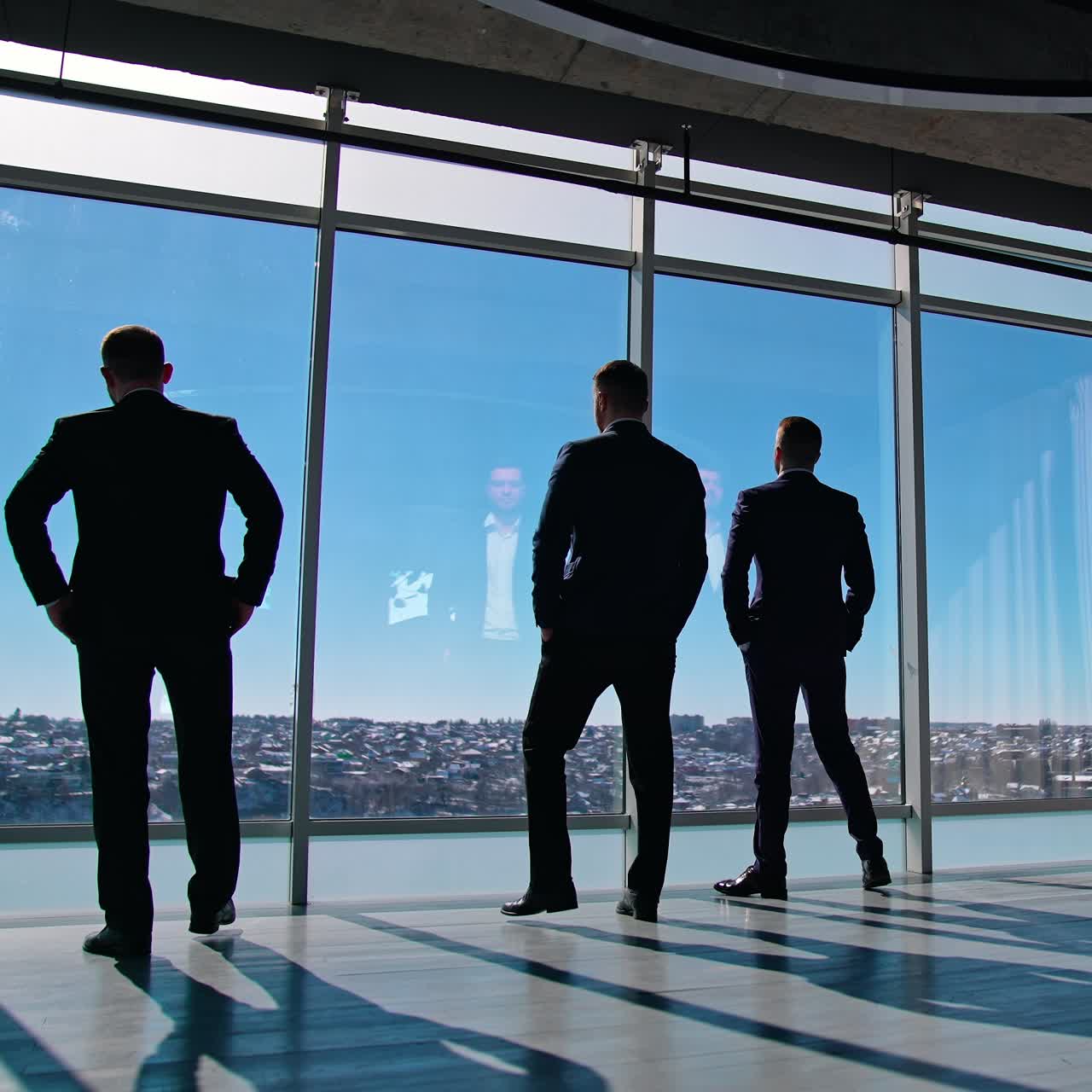 Business people moving to the large office windows. Three men in suits walking to windows during break. Elegant entrepreneurs indoors. Slow motion