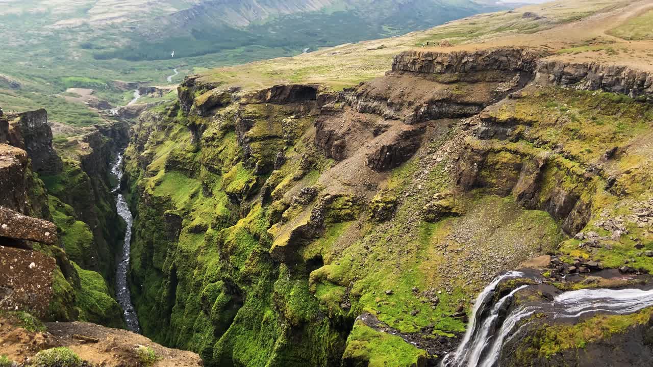 mirando por encima del borde de la cascada de glymur, haciendo una toma panorámica