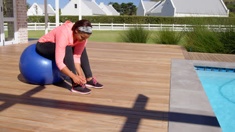 side view of mature mixed-race woman tying shoelaces in backyard of their home 4k