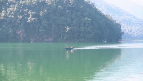 a three manned boat paddling fast to return to the shore of the fewa lake, pokhara