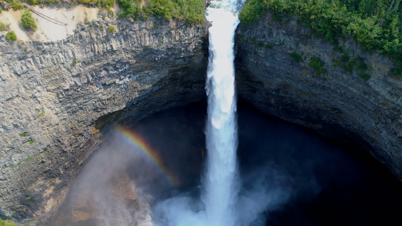 hermosa caída de agua a través del acantilado del bosque en un día soleado 4k