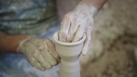 potter working white clay piece