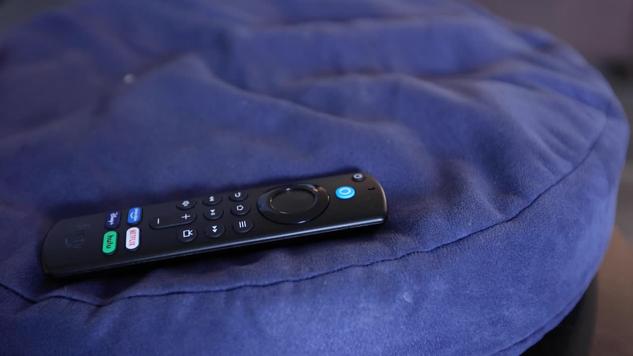 tv 룸의 커피 테이블에 있는 베개에 있는 tv 리모콘